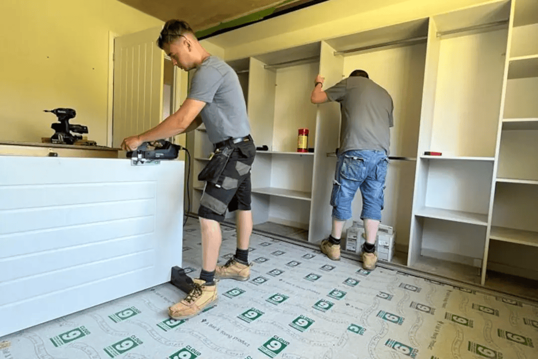 Builders Fitting Bespoke Storage Two builders fitting bespoke storage units during an interior renovation