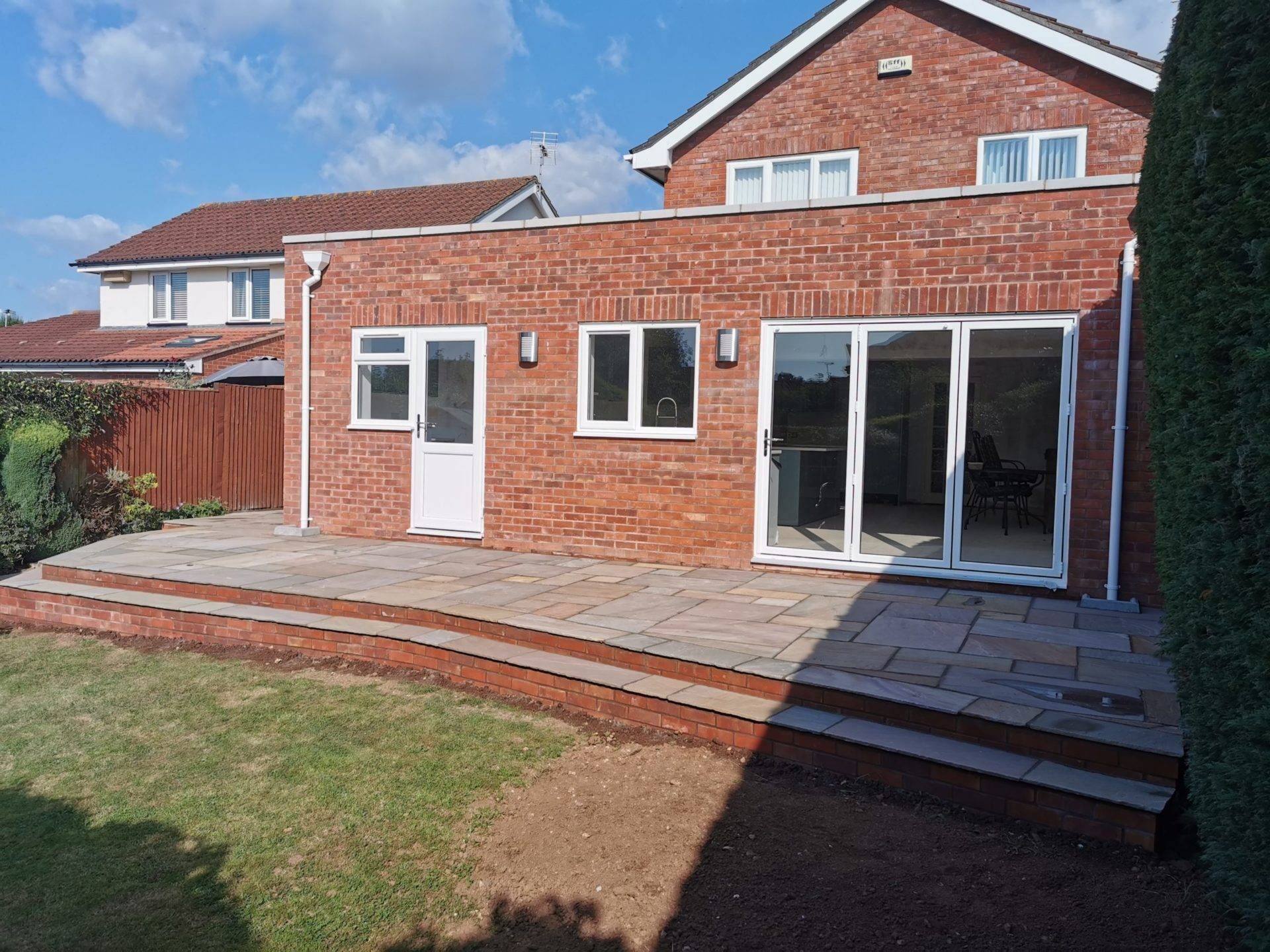 Completed red brick rear house extension with doors, windows and patio